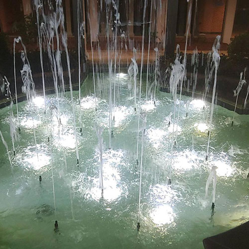 Fountain with water spraying upwards and lit up by lights underwater